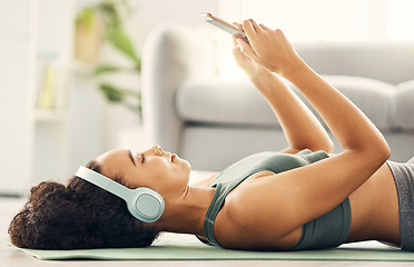 Image showing Phone, relax and yoga woman with music headphones on living room floor for fitness, break or texting at home. Workout, rest and sporty lady with smartphone and earphones for wellness, app or podcast