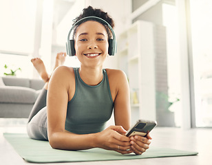 Image showing Yoga, portrait and happy woman relax on a living room floor with music, headphones and phone for streaming at home. Face, smile and lady on fitness break with social media, radio or podcast in lounge