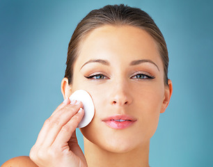 Image showing Skincare, portrait and woman with cotton pad on face, cosmetics and cleaning product for makeup. Dermatology, skin care and wellness for model with beauty, detox and facial glow on blue background.