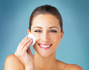 Image showing Dermatology, portrait and happy woman with cotton pad on face, skincare and makeup cleaning product. Cosmetics, skin care and wellness for model with beauty, detox and facial glow on blue background.