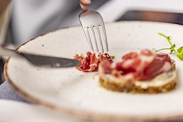 Image showing Person eating bruschetta with prosciutto