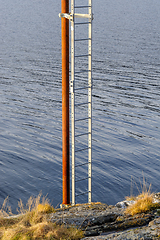 Image showing ladder that stands vertically up from the rock by the sea with t