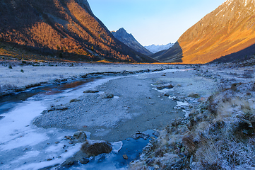 Image showing frozen landscape in the foreground with ice in a river flowing t