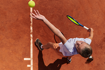 Image showing Top view of a professional female tennis player serves the tennis ball on the court with precision and power