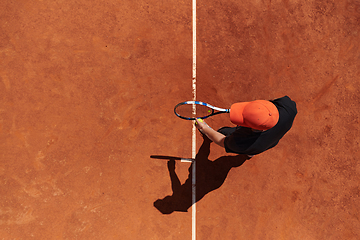 Image showing Top view of a professional tennis player serves the tennis ball on the court with precision and power