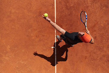 Image showing Top view of a professional tennis player serves the tennis ball on the court with precision and power