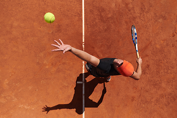 Image showing Top view of a professional tennis player serves the tennis ball on the court with precision and power
