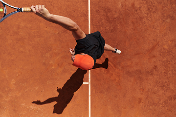 Image showing Top view of a professional tennis player serves the tennis ball on the court with precision and power