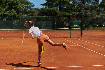 Image showing The tennis player focuses intently, perfecting her serve on the tennis court with precision and determination, displaying her dedication to improving her skills.