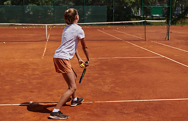 Image showing The tennis player focuses intently, perfecting her serve on the tennis court with precision and determination, displaying her dedication to improving her skills.
