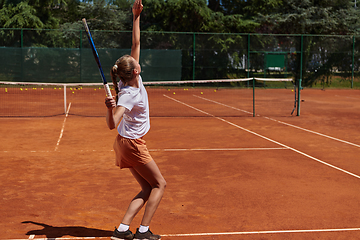 Image showing The tennis player focuses intently, perfecting her serve on the tennis court with precision and determination, displaying her dedication to improving her skills.