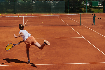 Image showing The tennis player focuses intently, perfecting her serve on the tennis court with precision and determination, displaying her dedication to improving her skills.