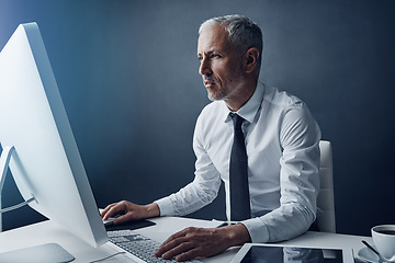 Image showing Typing accountant, computer and senior man in studio, working and isolated on a dark background mockup. Focus, writing and serious manager at desktop for reading email, research or business auditor.