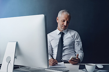 Image showing Phone, computer and business man at desk online for social media, internet and browse website in office. Networking, corporate worker and mature male person on smartphone, writing notes and planning