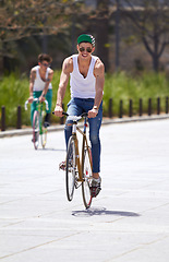 Image showing Men, summer and students in street, bicycle and sustainable transport for sunshine, freedom and wheelie. Young gen z people, retro bike and outdoor together in road for travel, university or campus