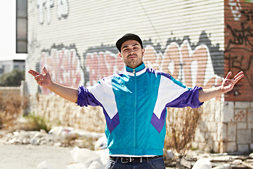 Image showing Graffiti artist, city and portrait of man in street stand by art, illustration and creative wall design. Fashion, gangster and person with hand sign in trendy, urban streetwear and casual clothes