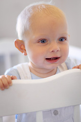 Image showing Happy, children and baby in the crib of a nursery in his home for growth, child development or curiosity. Kids, bedroom and toddler with a male or boy infant standing in his cot looking adorable