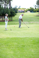 Image showing Old couple, sports or golfer playing golf for fitness, workout or exercise to swing on a course or field. Senior woman, elderly man golfing or training in practice game and driving with a club stroke