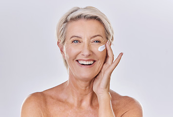 Image showing Portrait, cream on face and beauty with old woman, happy with skincare and dermatology on white background. Sunscreen, moisturizer and glow, female model apply lotion with glass container and skin