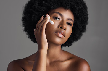 Image showing African woman, face cream and studio portrait with afro, skincare or cosmetic by grey background. Girl, model and healthy with natural glow on skin with makeup, clean aesthetic and product for beauty