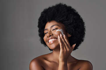 Image showing Beauty, skin care and black woman with lotion on face, afro and cosmetics in studio on grey background. Natural skincare, collagen cream and African model with salon glow, dermatology and wellness.