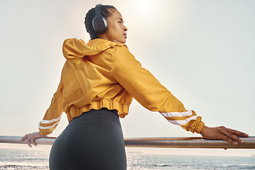 Image showing Headphones, thinking and woman at ocean for exercise, fitness or running mindset, goals and inspiration music. Health, podcast and athlete, runner or sports person behind by beach listening to audio