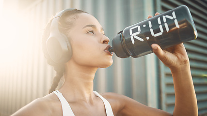 Image showing Headphones, runner or girl drinking water in city to hydrate, relax or healthy energy on exercise break. Tired, thirsty or fit athlete woman with liquid for hydration in fitness training or workout