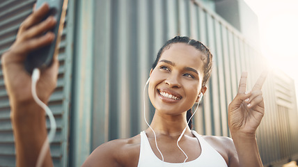 Image showing Fitness, selfie or happy woman in city with peace sign listening to music or radio in sports exercise. Mobile photography, smile or girl athlete runner taking pictures in training workout outdoors