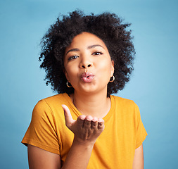 Image showing Woman, blowing kiss and beauty with makeup, flirt in studio with t shirt isolated on blue background. Young female model, cosmetics and pout, emoji and care free with casual fashion and gen z youth