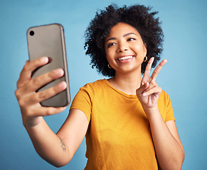 Image showing Selfie, peace sign and young woman isolated on blue background for social media or content creation. Gen z, youth and african person or influencer with online profile picture and emoji in studio