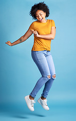 Image showing Excited, happy or woman celebrate, jumping or winning with opportunity, energy or dancing. Female person, model or girl in the air, dance or excitement with victory or fun on a blue studio background