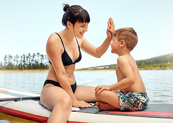 Image showing Lake, mother and son on paddle board, high five and relax outdoor, summer holiday and travel. Adventure, freedom and fun, family with woman and boy child in swimsuit, vacation and bonding together