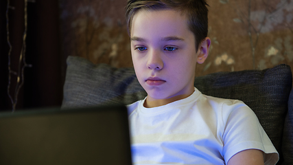 Image showing Kid boy or teen learning at home on laptop for school.