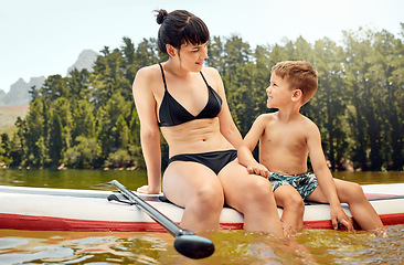 Image showing Lake, woman and boy child on paddle board, relax outdoor with summer holiday and travel. Adventure, freedom with mother and son in swimsuit with feet in water, vacation and family bonding together