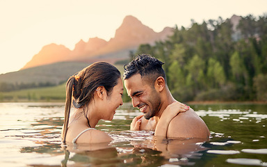Image showing Man, woman and hug with swim in lake, sunset and forest with love, bonding and vacation in summer. Young happy couple, outdoor and water for holiday together in sunshine with care, laugh or freedom