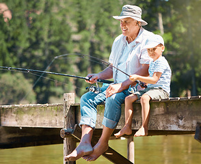 Image showing Grandfather, boy and fishing rod at lake for hobby, adventure and teaching about nature. Young child, senior man and learning to fish at water by river dock, weekend camping trip and outdoor holiday