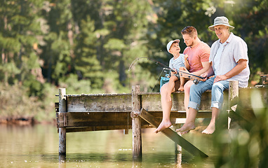 Image showing Dad, grandfather and child fishing at lake together for fun bonding, teaching or activity in nature. Father, grandpa and kid learning to catch fish with rod by water pond or river in forest outdoors