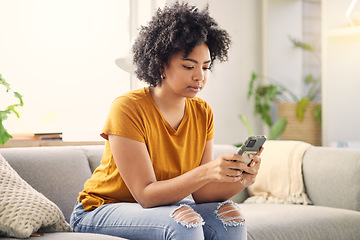 Image showing Phone, relax and woman on sofa in home living room for social media, internet scroll or texting. Mobile, serious or African person on couch in lounge for online app, website or reading email in house