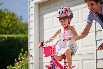 Image showing Child learning from dad to ride a bicycle as support, trust and skill development outdoor of a home or house together. Parent, safety and happy father care, help and teaching kid or girl to use bike