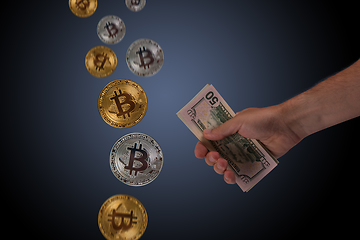 Image showing Hand holding dollar money and bitcoin on blue dark background