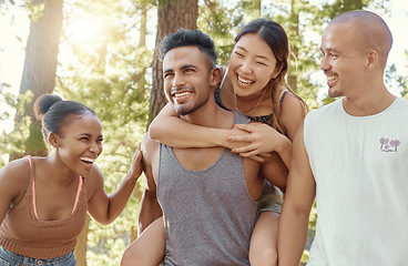 Image showing Happy friends, laughing and piggyback in forest for fun holiday, weekend or vacation in the nature outdoors. Men and women enjoying funny time together in friendship on camping trip or walk in woods