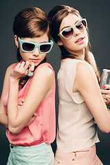 Image showing Fashion, beauty and retro with portrait of women in studio for elegant, pastel and vintage. Sunglasses, confident and cosmetics with female model on dark background for glamour, beehive and style