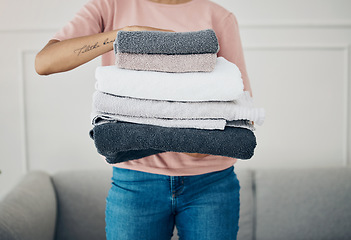 Image showing Towels, hands and cleaning with a woman housekeeper closeup in the living room of a home for hygiene. Laundry, housekeeping and chores with a female cleaner carrying a pile of washing in her house