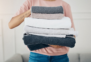 Image showing Towels, laundry and cleaning with a woman housekeeper closeup in the living room of a home for hygiene. Hands, housekeeping and chores with a female cleaner carrying a pile of washing in her house