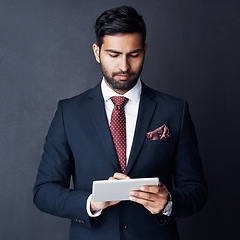 Image showing Serious, business man and tablet in studio, dark background and app for trading, planning or internet research. Corporate broker, indian male trader or focus on digital technology, online and website