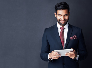 Image showing Happy, business man and tablet on dark background in studio with mockup space for trading, planning and internet research. Corporate, indian male trader and smile for digital technology of online app