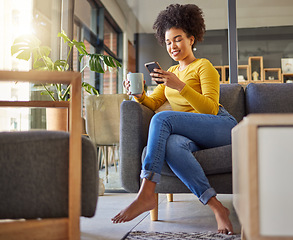 Image showing African woman, texting and phone on living room sofa, coffee and smile for chat, contact or meme on web. Girl, smartphone and reading on social media app, blog or video on internet on lounge couch