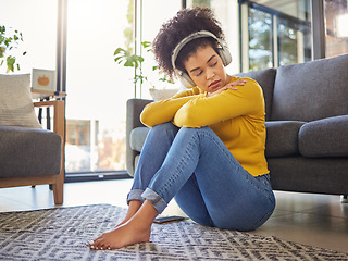 Image showing African woman, sad and headphones on floor with worry, stress or memory of trauma in home living room. Gen z girl, anxiety and remember mistake, regret or mental health with music in apartment lounge