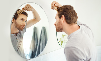 Image showing Bathroom, mirror and man brush hair for growth maintenance, texture grooming or morning cleaning routine. Salon, reflection or home person with sustainable bamboo comb for healthy hairstyle treatment