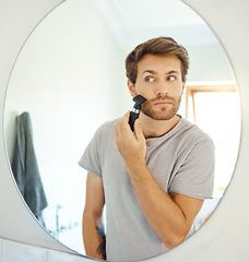 Image showing Mirror, grooming and a man shaving in the bathroom of a home in the morning for personal hygiene. Electric razor, reflection and morning routine with a young male person in his home for hair removal